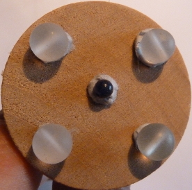 A round wooden disc with a stick to hold it, with 4 frosted quartz aligned to the corners of a square and a central indigo focus indigo energy with the energy of 4 and the cube